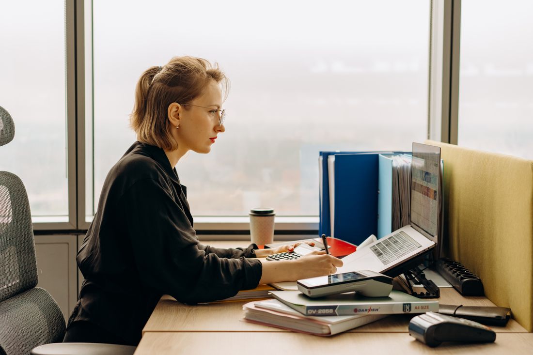 An accountant focused on a client's books at a bright office desk